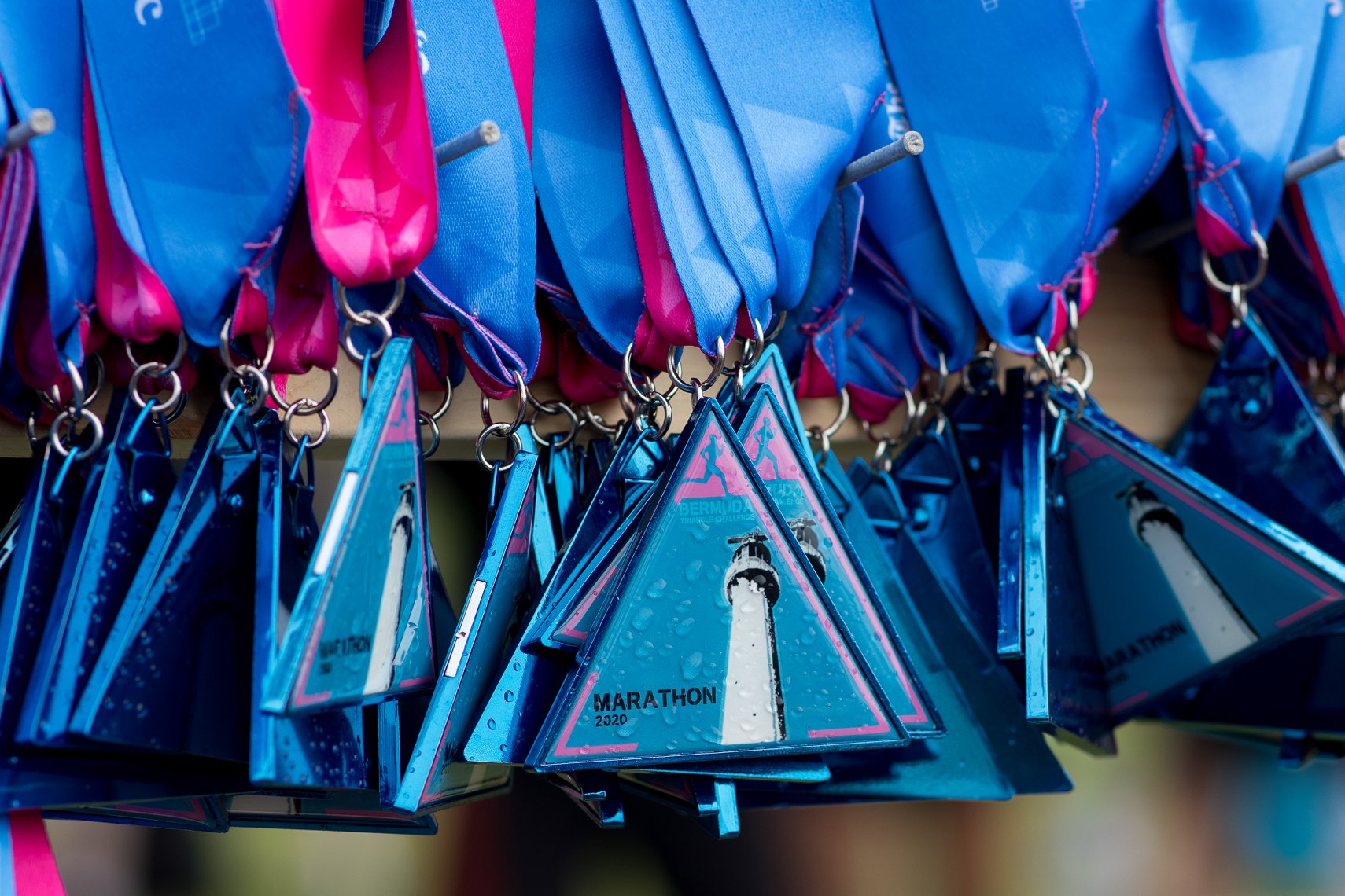 A row of Bermuda Marathon finisher's medals hang on a display rack